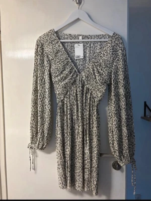 Blommig kortklänning med v-ringning - Supersöt kortklänning med svartvitt blommönster. Aldrig använd!