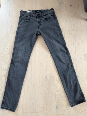 Gråa slim fit jeans från replay - Säljer ett par gråa slim fit jeans från replay Jeans med klassisk femficksmodell och svarta sömmar. Jeansen har en snygg tvättad look och är tillverkade i mjuk bomullsdenim med lite stretch för extra komfort.
