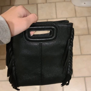 Svart väska med fransar från Maje - ❤️❤️❤️Säljer min fina maje Väska för den kommer tyvärr inte till användning längre. Man får med båda banden. ‼️ÄKTA, FÖRST TILL KVARN‼️