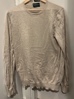 Beige stickad tröja från Alan Paine - Snygg och stilren beige stickad tröja från Alan Paine i lyxig bomull. Tröjan är i mycket bra skick och har använts lite men är nyss tvättad och inte struken så det är därför den ser lite sliten ut. Pris kan diskuteras!
