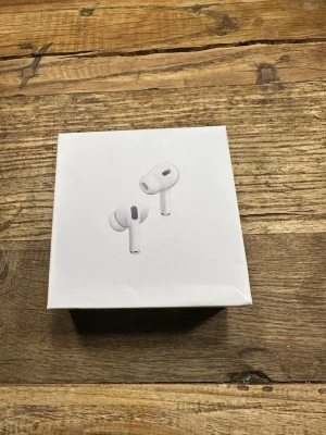 Apple AirPods Pro trådlösa hörlurar 2022 - Säljer ett par Apple AirPods Pro som är HELT NYA med laddningsetui, USB-C till Lightning-kabel och extra öronproppar. Hörlurarna är vita, har en stilren och kompakt design i plast och levereras i originalförpackning. Perfekta för musik, samtal och träning.