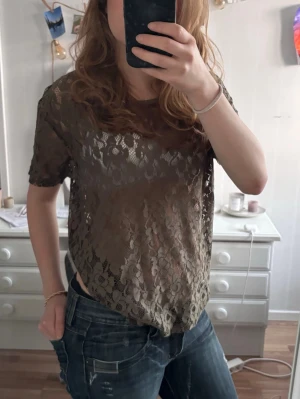 Grön spetstopp - Säljer en grön, kortärmad blus/topp i spets med blommigt mönster. Perfekt för att styla lager på lager. Superfin till både jeans och kjol! Aldrig använd💕sitter som en S/M