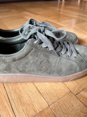 Grå Fred Perry sneakers - Snygga sneakers i grå mocka från Fred Perry med klassisk logga vid sidan. De är i storlek 40. De har även några tecken på slitage som man kan se på sista bilden. Men inget man lägger stor märke till. Skicka gärna prisförslag!💗