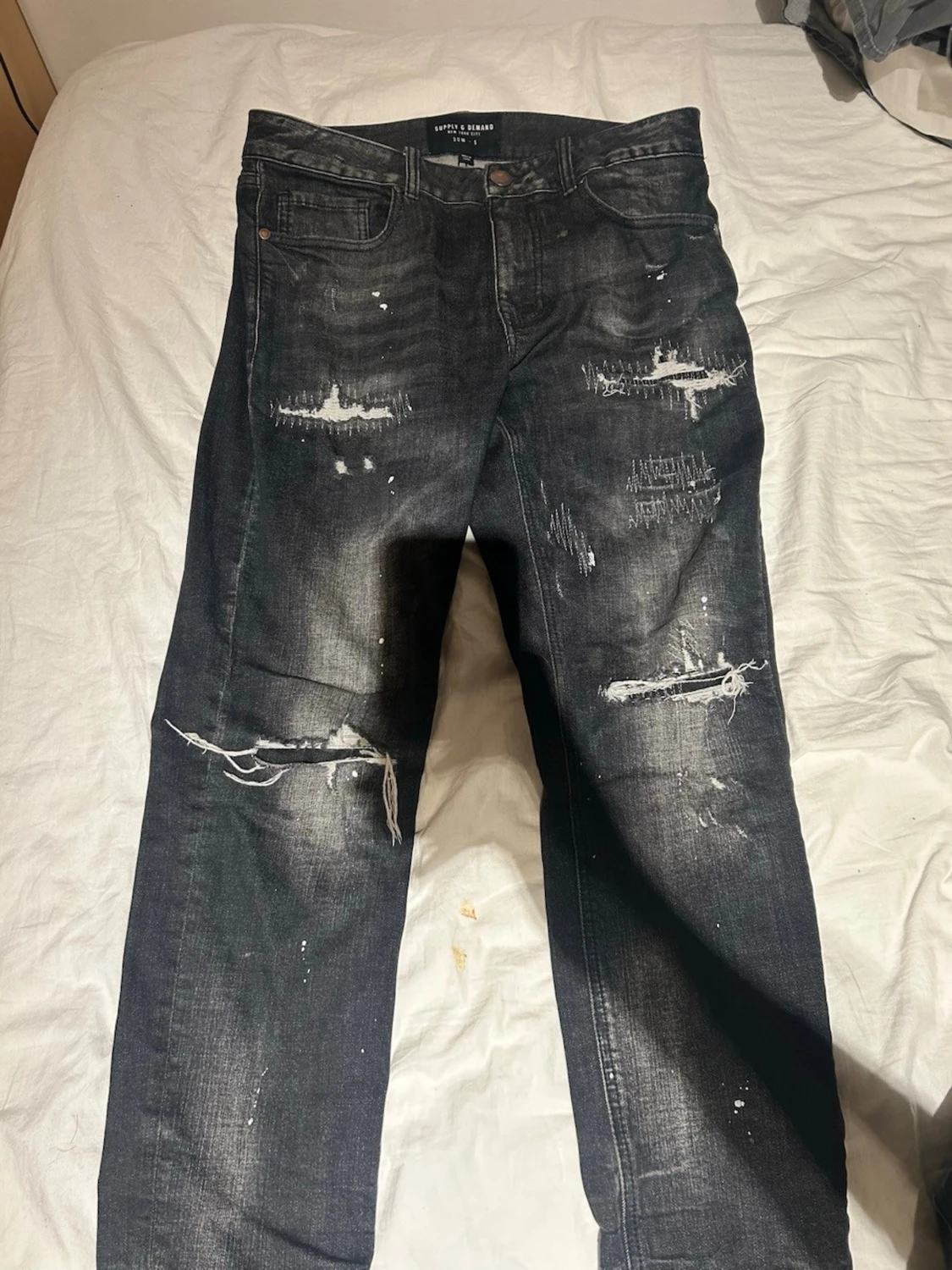 Svarta slitna jeans Supply & demand