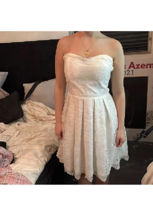 Snyggaste spets studentklänning ❤️ - Säljer en söt vit axelbandslös klänning med spetsdetaljer och lätt utställd kjol. Klänningen har dragkedja i ryggen och en romantisk känsla, perfekt för sommarens tillfällen. Passformen är normal och längden är kort. Passar finare på längre tjejer då den sitter kortare, jag är bara 1.58 lång😁