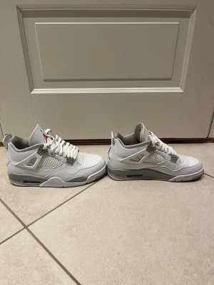 Jordan 4 Oreo - Säljer ett par fräscha vita Air Jordan 4 Retro sneakers med grå och svarta detaljer. Skorna har meshpaneler på sidorna, klassisk snörning och den ikoniska Jumpman-loggan på plösen. Ovandelen är i läder och mesh, sulan är tjock och har synlig Air-enhet. Finns box.