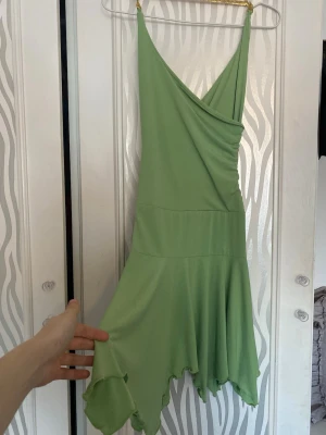 Ljusgrön omlottklänning med volang - Snygg ljusgrön kortklänning med omlottdesign och volangkantad nederdel. Klänningen har smala axelband och ett flowy fall som ger en riktigt somrig vibe. 2000s deadstock 