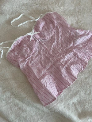 Rosa randigt linne med spetskant - Sött ljusrosa linne med ränder och vita spetsdetaljer. Justerbara axelband och liten rosett framtill. Från shein