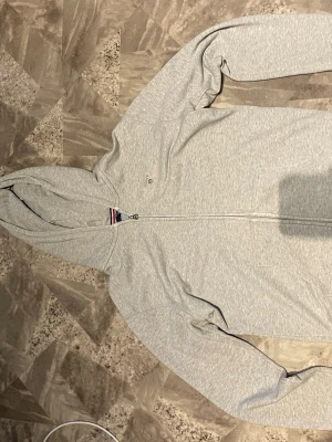 Ljusgrå zip-hoodie från Gant - Ljusgrå hoodie med dragkedja från Gant. Klassisk design med huva, fickor framtill och diskret Gant-logga på bröstet. 