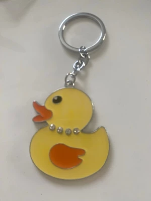 Nyckelringar med anka och björn - Två söta nyckelringar i metall och emalj, en i form av en gul anka med orange näbb och detaljer samt en brun björn med beige mage och ansikte. Perfekta att hänga på väskan eller nyckelknippan för en lekfull touch. 55kr/st , helt ny , finns fler kvar 