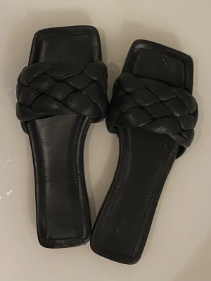 Svarta flätade sandaler H&M - Stilrena svarta sandaler från H&M med breda, flätade remmar och fyrkantig tå. 