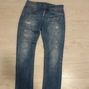 Blå slitna jeans från Nudie Jeans - Säljer ett par blå jeans från dondup med slitningar och hål på framsidan för en cool, avslappnad look. Säljs då de e för små och använts en gång bara, hör av er vid minsta fråga✌️🌟