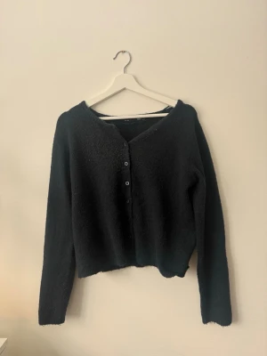 Svart kofta med knappar - Mysig marinblå kofta med knäppning framtill. Långärmad och i ett mjukt, lite fluffigt material. Lite nopprig framtill, men inget man tänker på. Storlek M, från Lager 157.