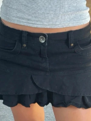 Svart volangkjol  - Supersöt svart kortkjol med dubbla volanglager och fickor fram. Kjolen har ett avtagbart bälte i leopardmönster. Köpte kjolen på en marknad i Spanien och säljer då den har blivit för liten!!🫰