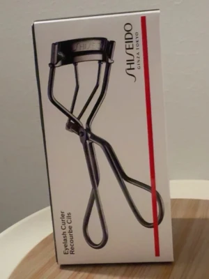 Shiseido ögonfransböjare svart metall - Shiseido ögonfransböjare i svart metall med ergonomiskt handtag och klassisk böjd form. Perfekt för att skapa snyggt böjda fransar snabbt och enkelt. Levereras i originalförpackning med stilren design.