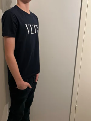 Valentino T-shirt  - Snygg svart t-shirt från Valentino med VLTN-tryck i vitt över bröstet. Klassisk rak passform och rund halsringning. Tillverkad i mjukt bomullstyg som känns skönt mot huden. Perfekt för dig som gillar stilrena och trendiga plagg. Den är i storlek S och är helt oanvänd! En riktigt fin T-shirt helt enkelt och vid frågor är det bara att höra av sig😁✌️