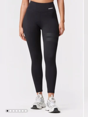 Svarta leggings från Stronger - Snygga svarta leggings från Stronger med hög midja och diskreta mönstrade ränder på låret. Tillverkade i stretchigt material som sitter tight och bekvämt. Perfekta för träning eller chill dagar Helt oanvända, sänkt pris.