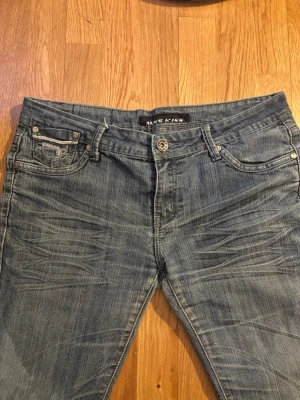 low waist jeans - Säljer ett par klassiska blå jeans från McKiss med raka ben och snygga slitningar framtill. Jeansen har fem fickor, normal midja och stängs med knapp och dragkedja. Perfekta till en avslappnad stil och passar till det mesta.
