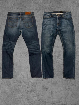 Tiger of sweden jeans - Säljer ett par blå slim fit jeans med snygga slitningar och tvättade detaljer på framsidan. Klassisk femficksmodell med läderpatch bak i midjan. Perfekta för dig som gillar en modern och avslappnad stil. Storlek 32/32 modell Evolve sitter slim.
