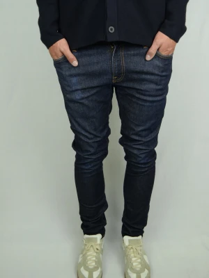 Nudie Jeans  - NUDIE JEANS Storlek : 33/32 Modell : Skinny Lin Mått : A = 42CM - B = 106CM - C = 15CM Användning : Jeansen är i ett fint skick, fadings på vissa ställen men inga direkta defekter Nypris : Cirka 1700SEK Modellen på bilden : 182CM och väger 74KG