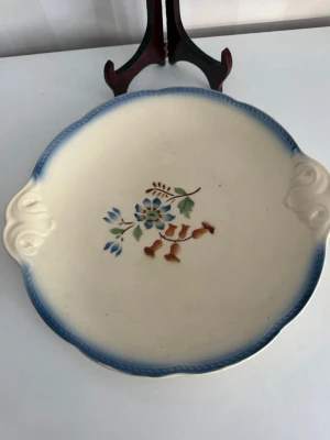 Vintage Gefle fat med blommotiv - Fint rundat fat i keramik med handtag på sidorna, dekorerat med blå och bruna blommor i mitten och blå kant. Perfekt som dekoration eller serveringsfat. Klassisk retrostil.