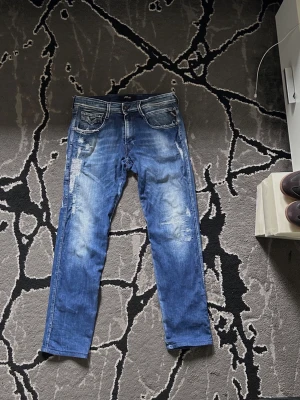 Replay Anbass - Säljer ett par blå Replay jeans med  snygga slitningar. Jeansen har klassisk femficksdesign och kontrastsömmar. Perfekta för en avslappnad och trendig look. Jensen är W31 L32, längden är 100cm och bredden är 41cm. Vid mer frågor är det bara att skitva till.(Priset kan diskuteras)
