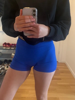 Blå ribbade träningsshorts - Säljer ett par blå ribbade träningsshorts med hög midja. Shortsen är stretchiga och sitter tight, perfekta för gymmet eller yoga. Materialet är mjukt och följsamt, vilket ger bra rörelsefrihet.