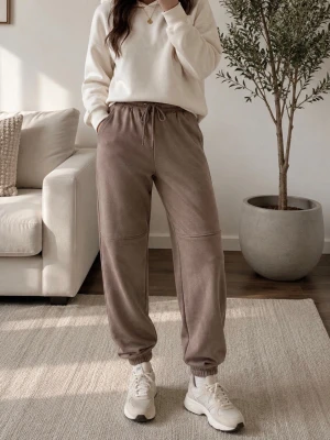 Beige mjukisbyxor med dragsko - Snygga beige mjukisbyxor med resår i midjan och dragsko, samt resår vid bensluten. Byxorna har två sidofickor och är tillverkade i ett mjukt och bekvämt material, perfekta för en avslappnad stil. Söm över knäna ger en extra detalj.