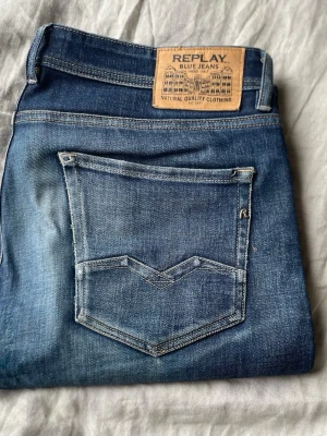 Replay Jeans - Snygga blå jeans från Replay, modell Rocco Comfort Fit. Klassisk femficksdesign med tydliga sömmar och läderpatch bak i midjan. Jeansen har en avslappnad passform och är tillverkade i slitstarkt denimtyg.
