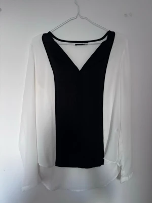 Svartvit blus från Vila - Snygg svartvit blus från Vila med lång ärm och v-ringning. Tunt, lätt material som ger en luftig känsla och en stilren look.