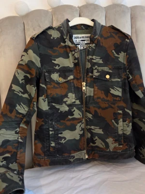Camouflage vindjacka Zadig & Voltaire - Snygg vindjacka från Zadig & Voltaire i klassiskt camouflage-mönster med gröna, bruna och svarta toner. Jackan har dragkedja framtill, två bröstfickor med knappar och en cool, rak passform.Säljer pågrund av att den ej komer till använding längre🥰Ge gärna förslag på priser🥹