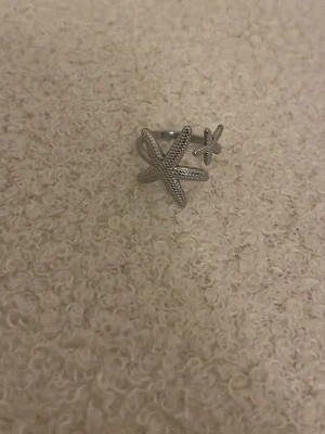 Sjöstjärnor ring - Säljer en silvrig ring med två sjöstjärnor, den är justerbar så passar alla storlekar 💕knappt använd