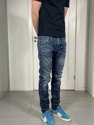 Replay Anbass jeans Mörkblå -  W32 L34 liten slitning på knät.                           säljer ett par blå slim fit jeans med snygga slitningar och tvättade detaljer. Jeansen har fem fickor, normal midja och klassisk dragkedja med knapp. Perfekta för en avslappnad och trendig stil.
