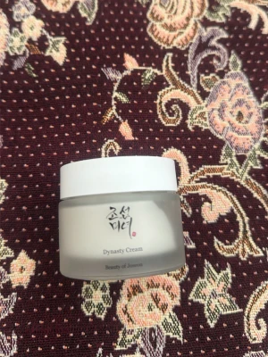 Dynasty Cream från Beauty of Joseon - En stilren ansiktskräm i frostad glasburk med vit plastlock från Beauty of Joseon. Krämen heter Dynasty Cream och är känd för sin återfuktande formula. Perfekt för dig som vill ha glow och mjuk hud.