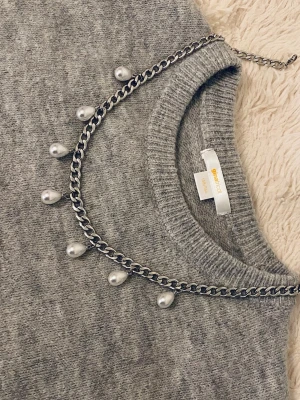 Kedjehalsband med pärlor - Snyggt halsband med en grov silverfärgad kedja och hängande vita pärlor. Kedjan har en modern, chunky stil och pärlorna ger en cool kontrast. Perfekt accessoar för att lyfta din outfit med en trendig touch.