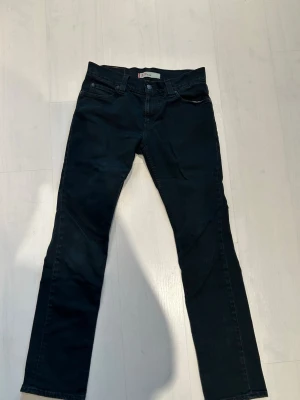 Svarta Levi's 511 Slim jeans W33 L34 - Snygga svarta jeans från Levi's modell 511 Slim. Jeansen har klassisk femficksdesign, smal passform och är tillverkade i ett stretchigt denimtyg för extra komfort. Perfekta för en trendig och avslappnad look. W33 L34