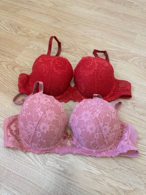 Två spetsbhar i rött och rosa - Två BHar med spetsdetaljer, en i rött och en i rosa