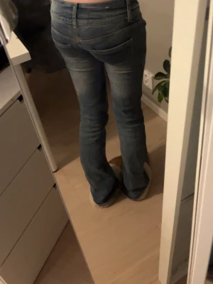 Blå bootcut jeans med låg midja - Säljer ett par blå bootcut jeans med låg midja och slitningar på låren. Jeansen har klassiska fem fickor och stängs med dragkedja och knapp. Har använt dom några gånger och säljer pågrund av att dom börjat bli försmå annars hade jag haft kvar dom, har även gjort om dom till lågmidjade det är alltså därför dom är så låga  almen håller bra och inget fel förutom ett litet hål som knappt syns lite på sidan av sömnen där jag sytt (alltså mellan benen) men går lätt att sy igen med nål och tråd.😊 