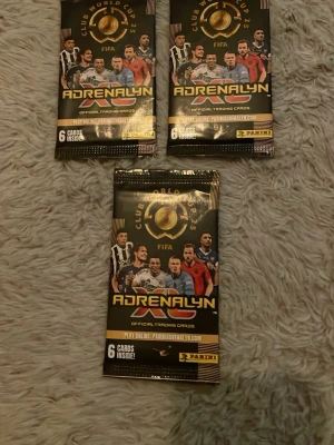 Panini Adrenalyn FIFA samlarkort - Tre oöppnade paket Panini Adrenalyn FIFA Club World Cups samlarkort. Varje paket innehåller 6 officiella trading cards. Svart och guld design med fotbollsspelare på framsidan. Perfekt för dig som gillar att samla fotbollskort.