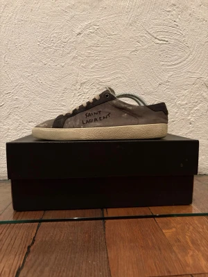 Yves Saint Laurent Sl06 grå(rare) - Ett par gråa Ysl sl06 sneakers med beiga detaljer, med skorna medkommer box, påse och andra småsaker som kort. Skorna är i väldigt bra skick och perfekta får sommaren. Skorna är storlek 41 men passar allt från 40 till 42,5. Fråga gärna vid funderingar! 👌