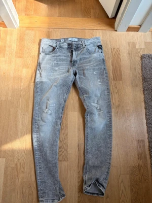 Grå slitna skinny jeans från Replay ( W32 ) - Säljer ett par grå skinny jeans från Replay med slitningar på låren och knäna. Jeansen har klassisk femficksmodell, normal midja och dragkedja med knapp. Perfekta för en avslappnad och trendig look.    
