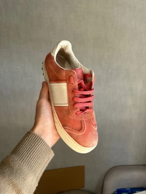 Valentino flycrews  - Snygga sneakers i rosa mocka med vita läderpaneler och matchande rosa skosnören. Skorna har en klassisk låg profil och vit sula som ger en stilren look. Perfekta för dig som vill ha en unik touch på din outfit.