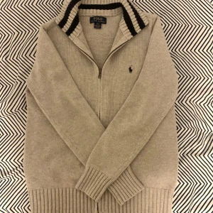 Ralph Lauren Stickad Cardigan  - Säljer nu denna tvärfeta stickade Ralph Lauren cardigan i nyskick. Använd max 3 gånger så finns inga tecken på användning. Storleken är L (14-16) men något större i storleken och jag uppskattar den därför som en XS-S ungefär. Jag är 175 och den sitter lite för tajt på mig som brukar ha S vanligtvis.. Hör av er vid frågor! 🫡🌟 Mått: Längd 57,5 cm Bredd under armhålorna: 45 cm