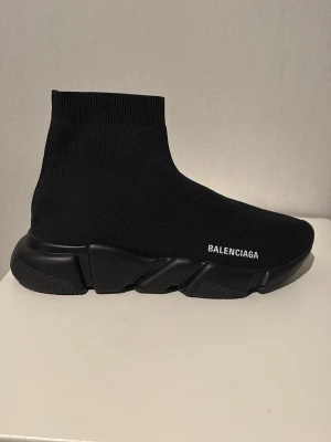Balenciaga Speed Trainer svarta sneakers - Svarta Balenciaga Speed Trainer sneakers med stickad ovandel i textil och chunky sula. Strumpliknande passform och vit logga på sidan. Minimalistisk design och riktigt bekväma att bära. Perfekta för dig som gillar streetwear och vill ha något stilrent.