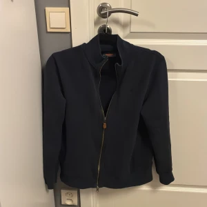 Mörkblå zip-jacka från Morris XS - Snygg mörkblå full zip från Morris i storlek S. Denna passar perfekt till vinter då en både är varm och snygg. Lite liten i modell, rekommenderas till 170-175 cm