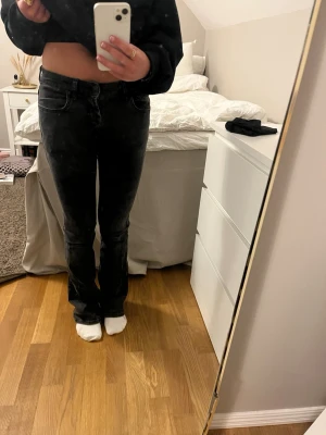 Svarta bootcut jeans från LTB - Svarta jeans från LTB med bootcut-modell och klassisk femficksdesign. Jeansen har låg midja och är tillverkade i ett stretchigt denimtyg som sitter snyggt över höfterna och låren. Perfekta för dig som gillar en lite utsvängd look. Lite söitna längst ner på benen och mellan benen fins det hål som försökts laga. Midjemått tvärs över:32cm innerbensmått: 80cm 