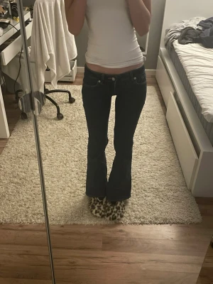 Mörkblå low waist bootcut jeans - Säljer ett par mörkblå bootcut jeans med klassisk femficksdesign och snygga kontrastsömmar. Jeansen har låg midja och är tillverkade i stretchigt denimtyg för skön passform. Perfekta för dig som gillar en classy look.