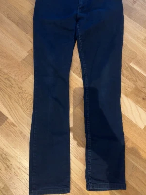 Mörkblå jeans från Armani Jeans - Snygga mörkblå jeans från Armani med klassisk femficksmodell och raka ben. Jeansen har diskreta sömmar och silverfärgade nitar med armani logga på. Tillverkade i ett mjukt bomullsmaterial med lite stretch för extra komfort. Perfekta för en stilren och avslappnad look.