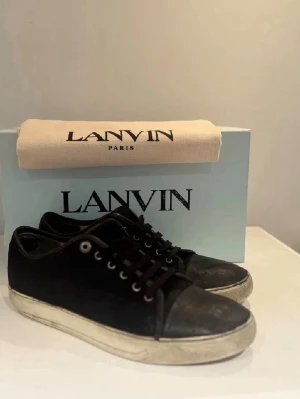 Svarta Lanvin sneakers med vit sula - Säljer min lanvin skor kvitto, dustbag + box tillkommer. Köpta på minto. Skick 6/10. Storlek 43 passar även 44. Lanvinsen är med den matta toeboxen som passar riktigt fint till den svarta mockan på skorna. Skorna är även nyimpregnerade inför vintern och den kommande våren. Tveka inte på att höra av dig. Pris är absolut diskuterbart vid en smidig affär✅