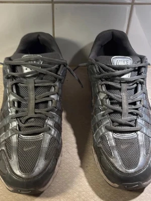 Nike p6000 - Säljer ett par svarta Nike sneakers med mesh- och syntetpaneler. Skorna har en sportig look med reflekterande detaljer och klassisk Nike Swoosh på sidan. Lågt skaft och snörning för skön passform. Perfekta för dig som gillar streetwear och sportig stil.